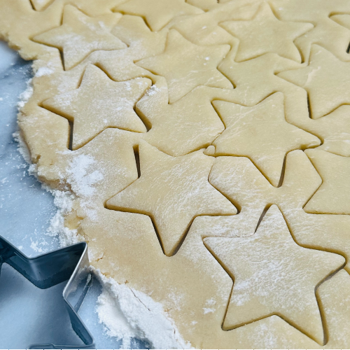 Cookie dough cut into star shapes using cookie cutters.